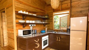 A compact kitchen with wooden walls, a built-in microwave, a stove, and a sink. - BAYLEAF: The Perfect Hideaway near secluded beach (Hellene)
