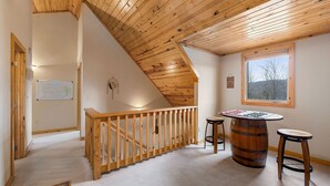A wooden interior with a staircase, a whiteboard, and a window with a view.