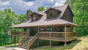 A wooden cabin with a porch and a staircase leading to a deck.