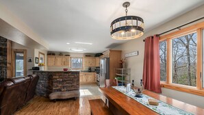 A spacious kitchen with wooden cabinets, a stone accent wall, a large island, and a view of a lake.