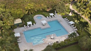 Luchtbeeld van een resort met een zwembad, ligbedden en palmbomen.