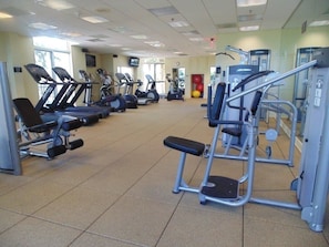 Un gimnasio con cintas de correr, elípticas y máquinas de pesas.