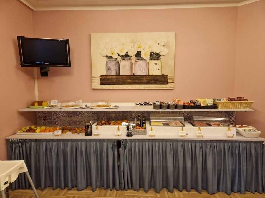 A buffet setup with various food items and a painting of flowers on the wall.