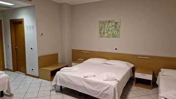 Una habitación de hotel con una cama, mesitas de noche, un banco y un cuadro en la pared.