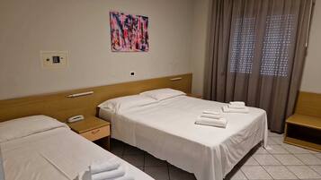 A hotel room with two beds, a bedside table with a phone, a painting on the wall, and a window with curtains.