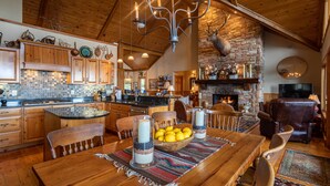 A spacious kitchen with wooden cabinets, a stone fireplace, and a dining area with a wooden table and chairs. - The Boulders: 5 Suites | Hot Tub | 50mi Views | Pool Table | Sauna | Wet Bar | Dog Friendly! (Boone)