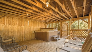 Eine Holzterrasse mit Whirlpool, Liegestühlen und einer Holzverkleidung.