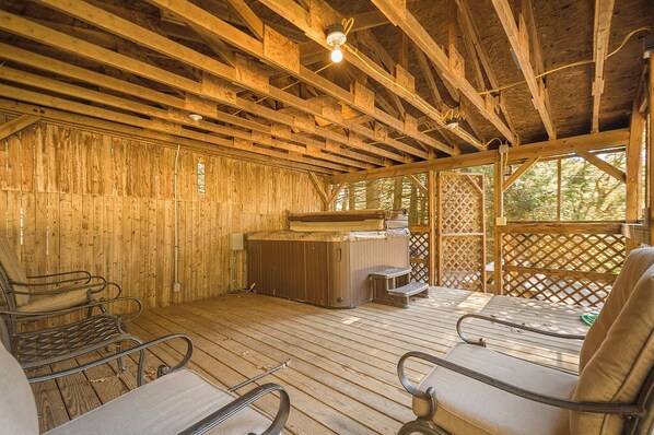 A wooden deck with a hot tub, lounge chairs, and a wooden wall.