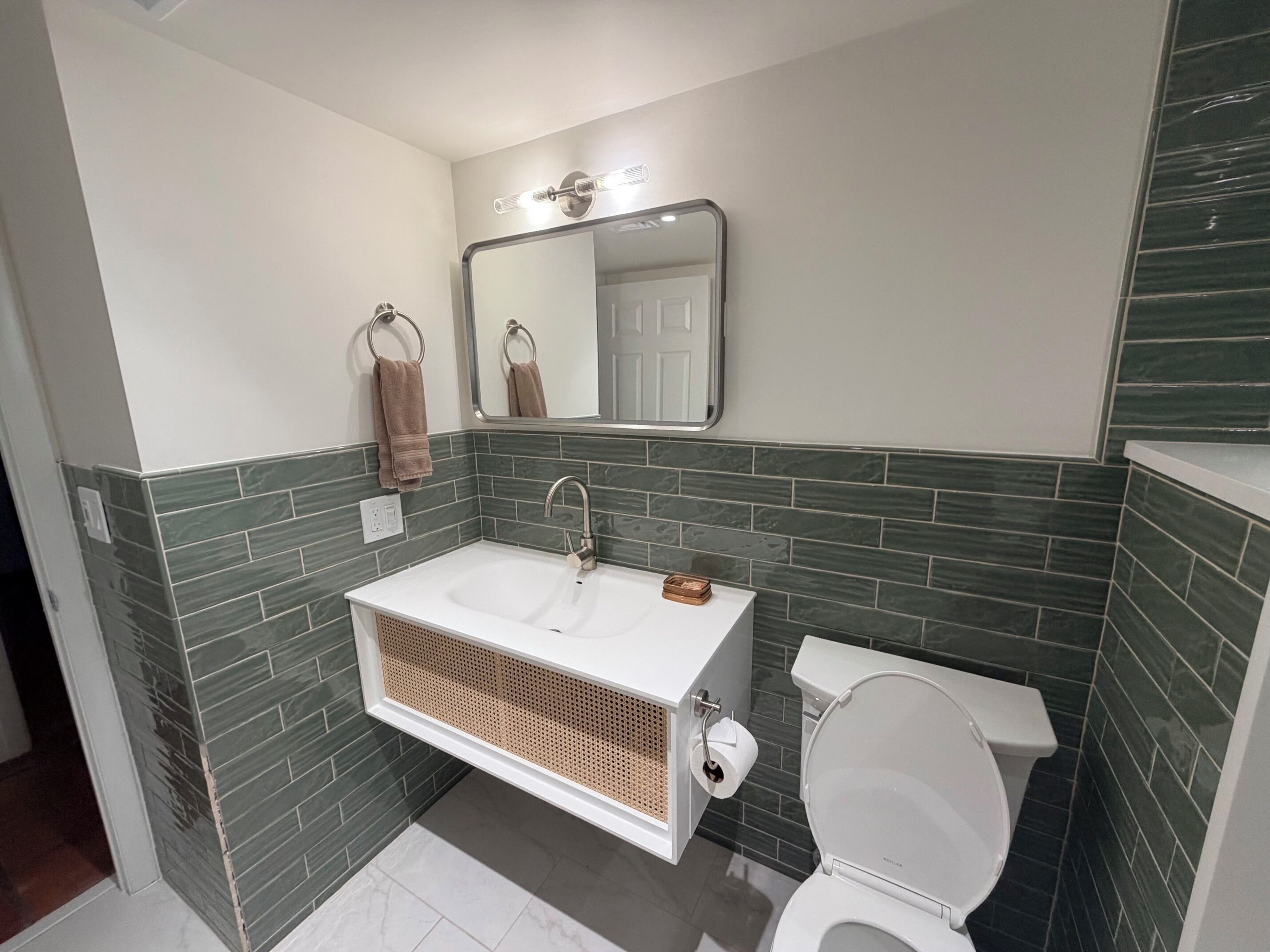 A bathroom with a white sink, a mirror above it, a towel rack, and a toilet.
