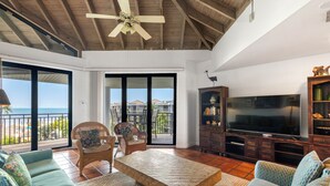 Un soggiorno spazioso con una grande TV, posti a sedere comodi e un balcone vista oceano.