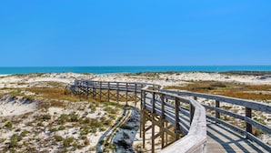 A wooden boardwalk leading to a beach with clear blue skies.