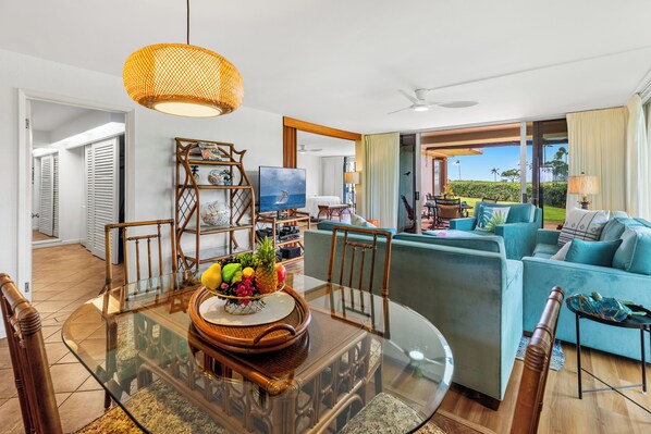 A modern living room with a glass dining table, a sofa, and a television.