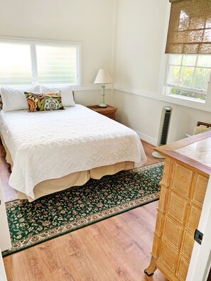 Quarto com cama grande, mesa de cabeceira com abajur, radiador e armário de madeira.