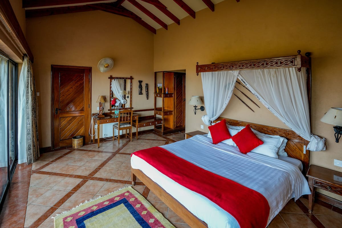 A bedroom with a large bed, a desk, and a chair.