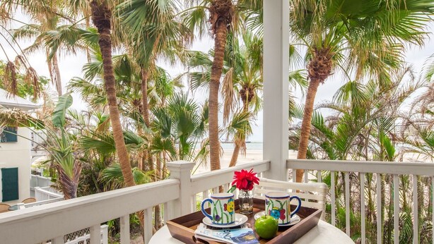 Een balkon met uitzicht op palmbomen en de zee.