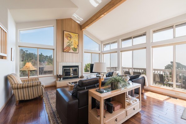 Un salón amplio con chimenea, ventanas grandes y un balcón.