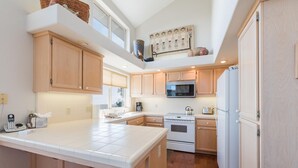 A modern kitchen with wooden cabinets, a large island, a microwave, a stove, and a refrigerator. - Pet-Friendly Home on Lodge Hill in Cambria Offers the Best Ocean Views! (Cambria)