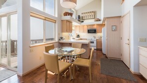 A modern kitchen with a glass dining table, wooden cabinets, and a large window. - Pet-Friendly Home on Lodge Hill in Cambria Offers the Best Ocean Views! (Cambria)