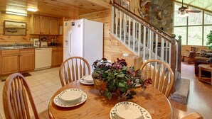 A wooden cabin interior with a kitchen, dining area, and a staircase leading to a loft. - Flat drive- 3BR cabin located between PF and GBurg with hot tub & game room! (Sevierville)