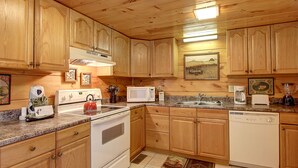 A kitchen with wooden cabinets, a stove, a microwave, a sink, and a dishwasher. - Flat drive- 3BR cabin located between PF and GBurg with hot tub & game room! (Sevierville)