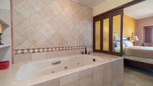 A bathroom with a bathtub, a mirror, and a shower area.