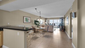 A spacious kitchen with a central island, a dining area with a round table, and a living area with a sofa and chairs. - Sand Key 714:  2 BR / 2 BA Gulf Front Condo in Perdido Key, FL  Sleeps 6 (Pensacola)