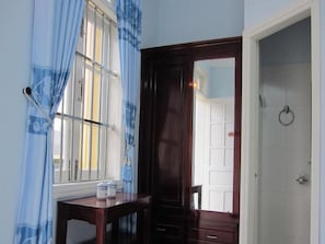 A room with a window, a wooden door, a small table with items, and a white wall.