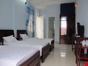 A hotel room with two beds, a television, a desk, and a bathroom visible through an open door.