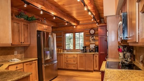 A spacious kitchen with wooden cabinets, stainless steel appliances, granite countertops, and a large window providing natural light. - Luxury Custom Log Cabin Retreat in Keystone/Large Private Patio (Keystone)