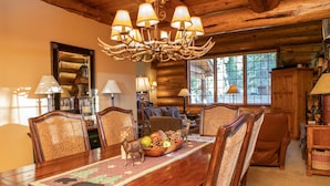 A wooden dining table with a fruit bowl centerpiece, surrounded by chairs with patterned upholstery. - Luxury Custom Log Cabin Retreat in Keystone/Large Private Patio (Keystone)