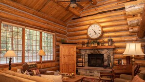 A log cabin interior with a fireplace, wooden furniture, and a large clock on the wall. - Luxury Custom Log Cabin Retreat in Keystone/Large Private Patio (Keystone)