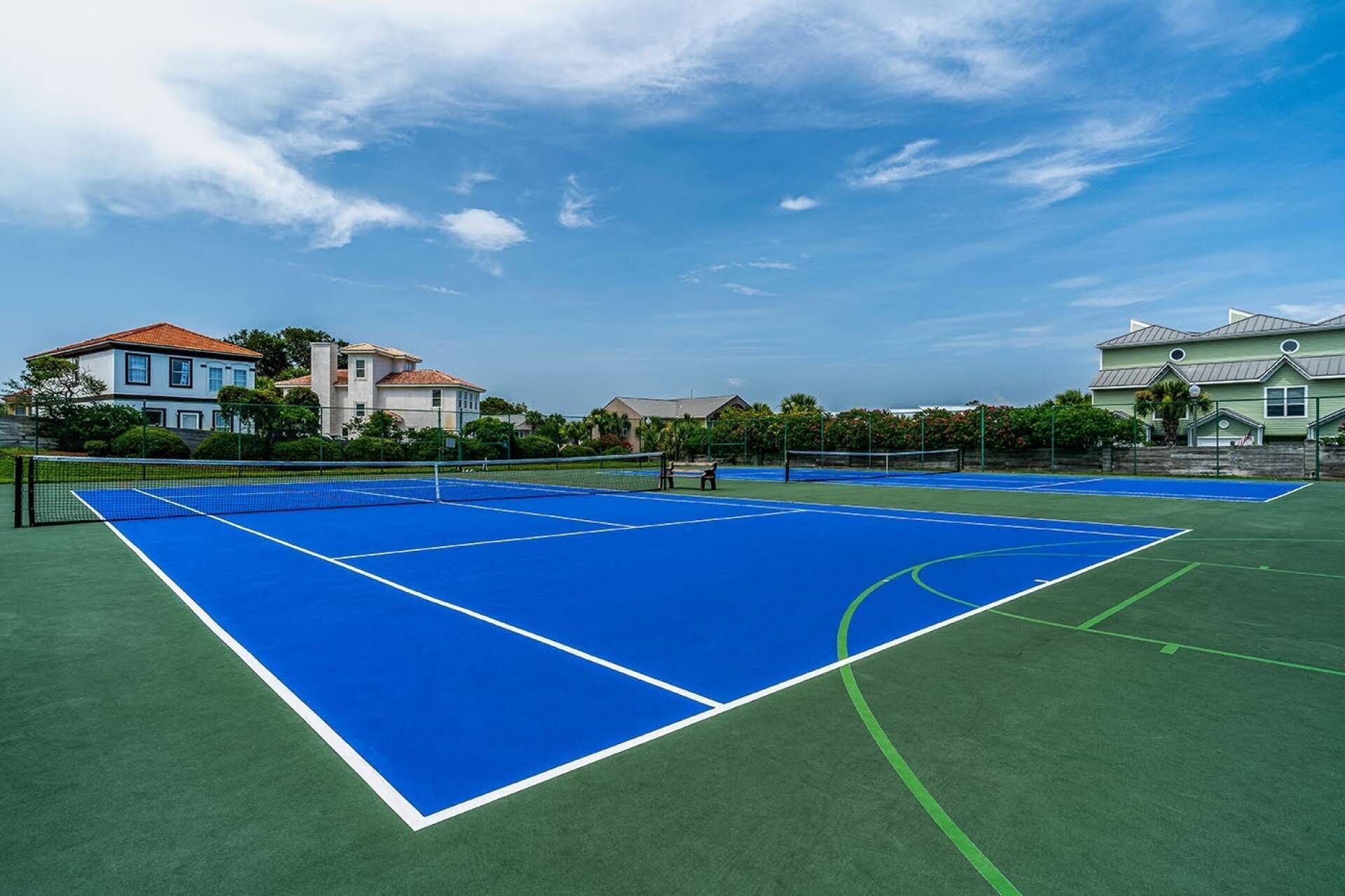 Ein Tennisplatz mit Netz, umgeben von grünem Gras und blauer Umrandung.