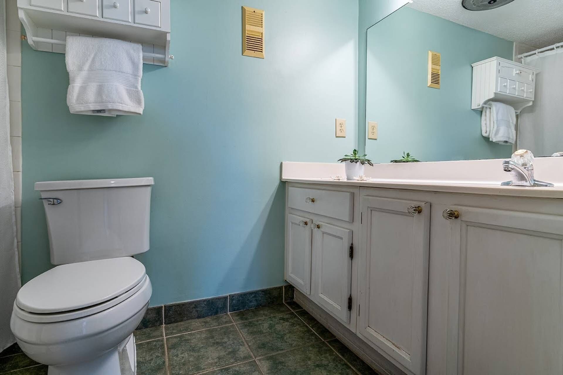 A bathroom with a toilet, a sink, and cabinets.