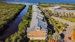 A coastal hotel with a long building overlooking a waterway, surrounded by greenery and a clear sky. - Hideaway Studio U619 Little Harbor Resort - Tampa Bay (Ruskin)