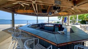 A beachside bar with a wooden ceiling, bar stools, and a view of the ocean. - Hideaway Studio U619 Little Harbor Resort - Tampa Bay (Ruskin)