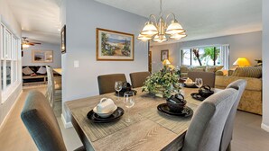 Een eetruimte met een houten tafel, stoelen en een kroonluchter. Er staat een kerstboom en hangt een schilderij aan de muur.