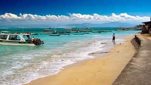 Une plage où plusieurs bateaux sont amarrés et où une personne se tient sur le rivage.