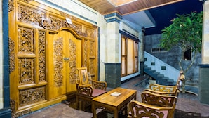 Une porte en bois richement décorée, ornée de sculptures complexes, une table en bois avec des chaises et un escalier menant à un niveau supérieur.