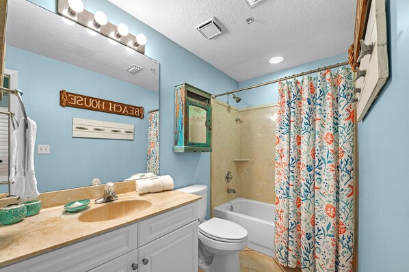 A bathroom with a sink, toilet, and shower curtain.