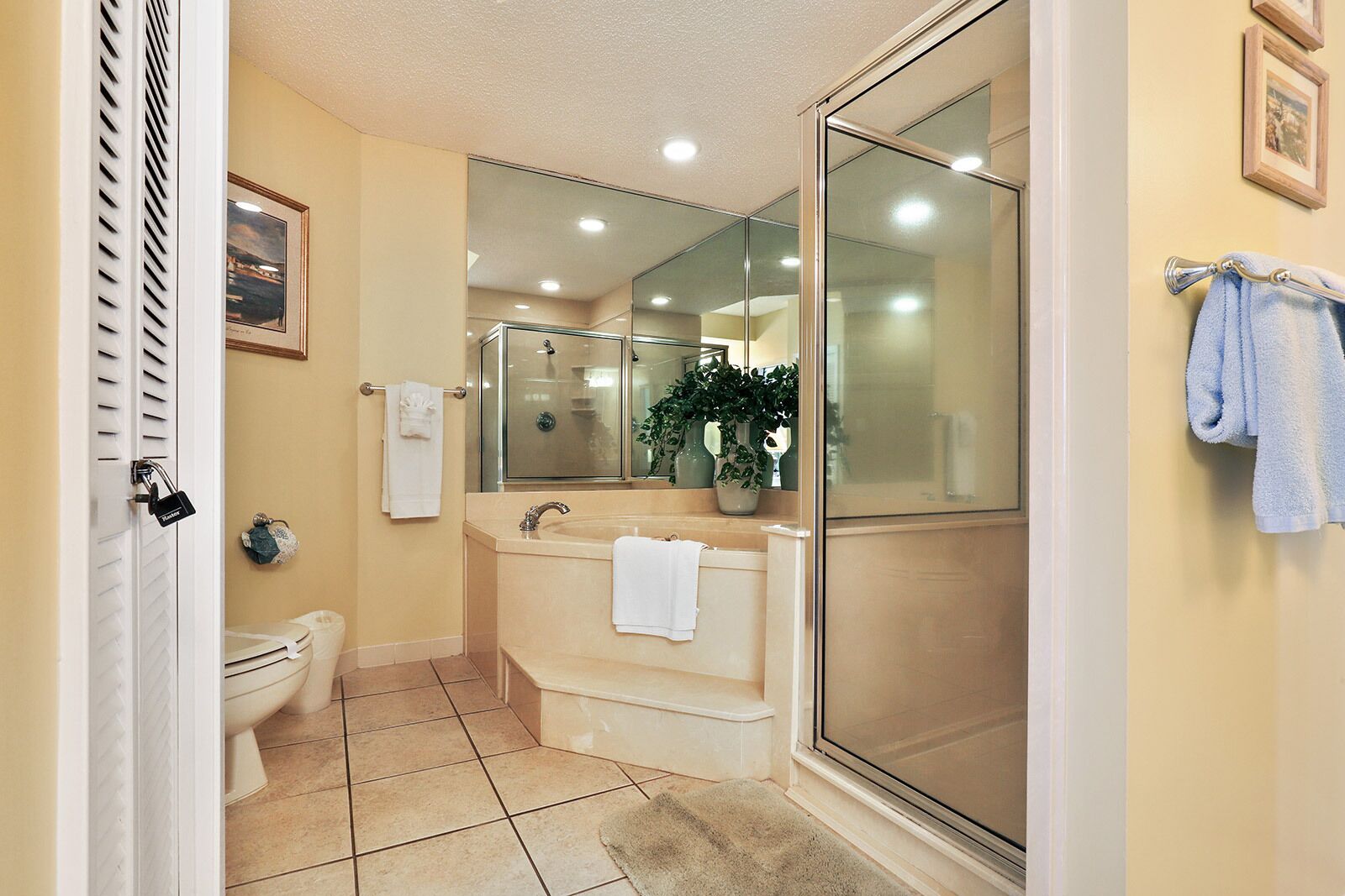Une salle de bain comprenant des toilettes, un lavabo, une douche et un espace de douche séparé par des parois en verre.
