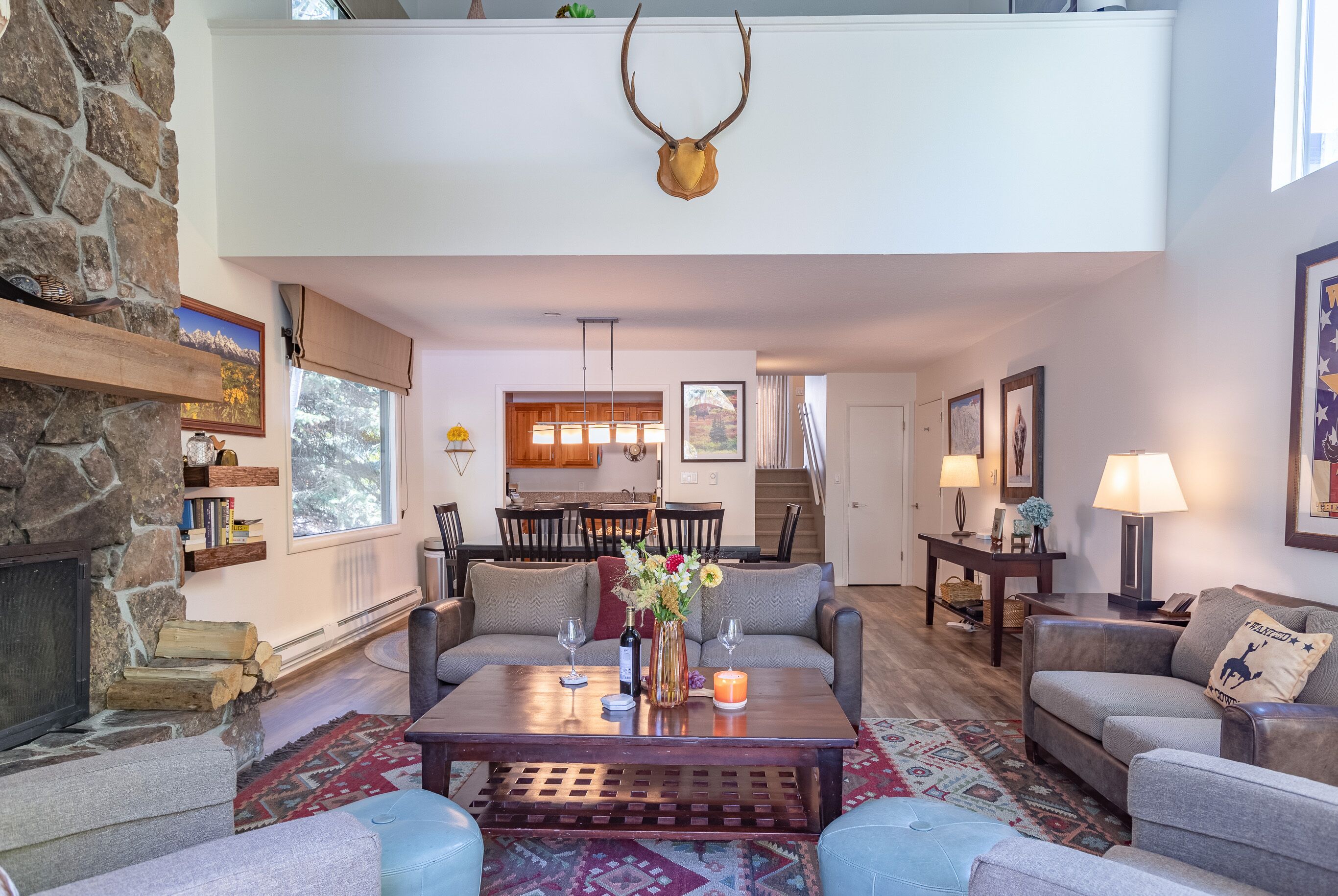 Un salon chaleureux avec une cheminée en pierre, une table basse en bois agrémentée d’objets décoratifs et un coin salon confortable avec un canapé et des fauteuils.
