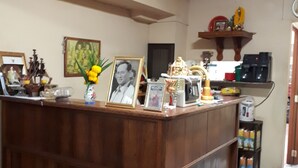 Ein Empfangsschalter mit gerahmten Fotos, einer kleinen Statue und einer Kaffeemaschine.