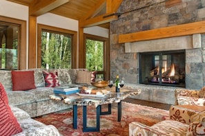 A cozy living room with a stone fireplace, a sofa set, and a table with snacks and drinks.