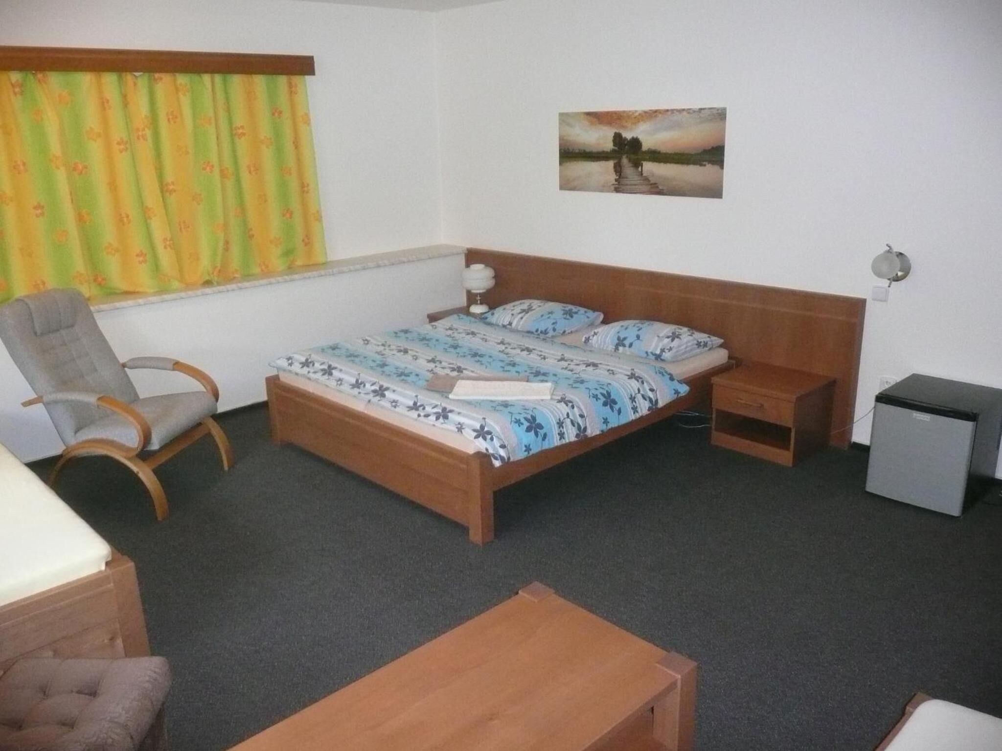 Une chambre avec un lit simple, une chaise, une petite table et un bureau.