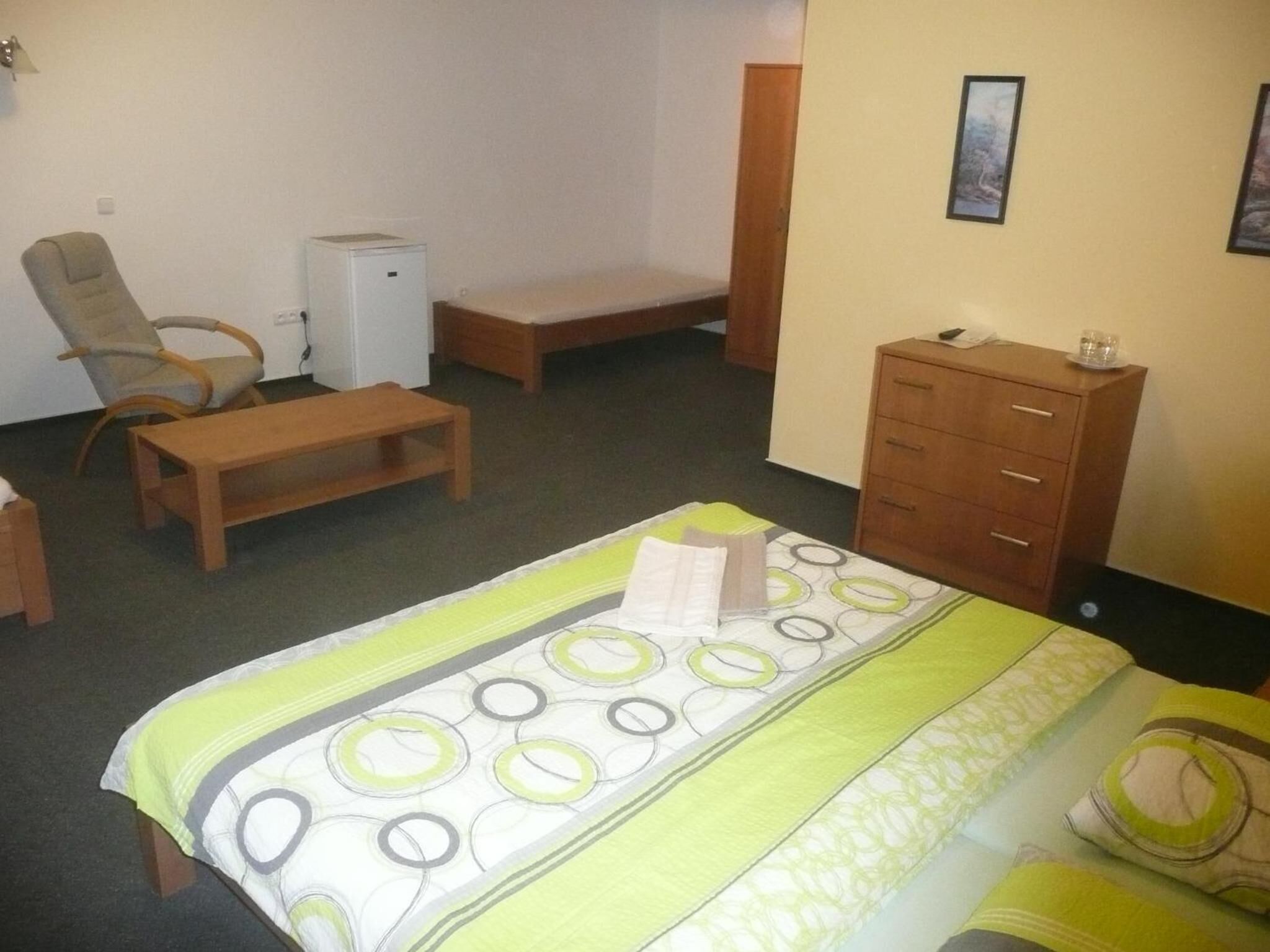 Une chambre d’hôtel comprenant un lit, une chaise, une petite table, une commode et un bureau.