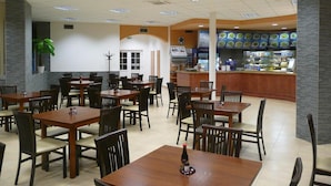 A restaurant with multiple tables and chairs, a counter with a menu display, and a potted plant. - Hotel Fojtů (Bruntal)