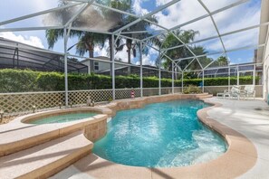 A pool area with a hot tub, surrounded by a covered patio with a lattice fence and palm trees in the background. - Magical 3BR Pool Home in Oak Island Harbor Close to Parks (Kissimmee)