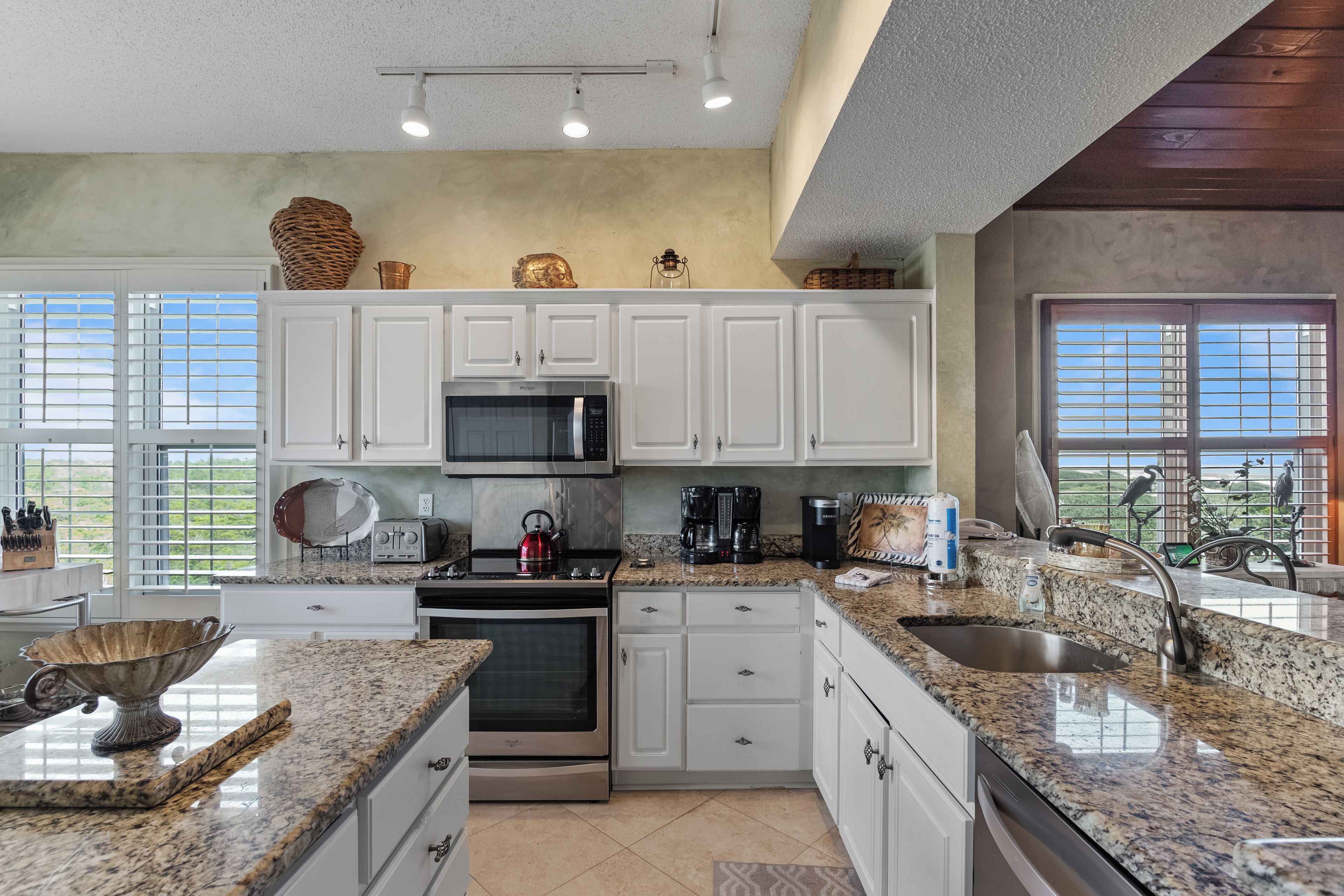 A modern kitchen with white cabinets, stainless steel appliances, and a granite countertop.