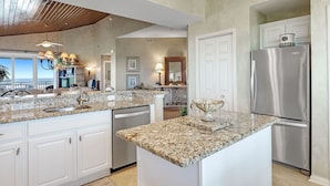A kitchen with granite countertops, stainless steel appliances, and a view to the outside.