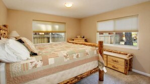 A bedroom with a bed, bedside tables, a window with blinds, and a ceiling light.